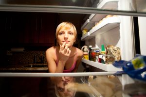 Woman thinking about her food choice inside refregirator