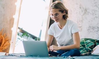 Young woman looking at laptop computer while sitting on bed