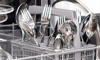 Dishwasher drawer open with cutlery and plates