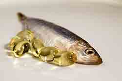 Fish oil capsules next to sprat