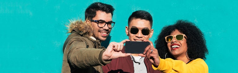 Group of friends taking group selfie with smartphone