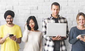 Group of people looking at different devices including laptops and mobile phones