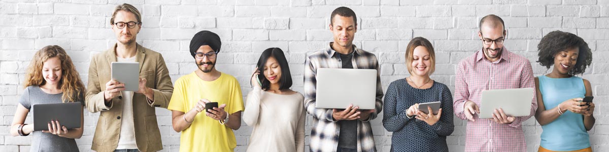 Group of people looking at different devices including laptops and mobile phones