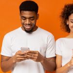Young adults using phones against orange background