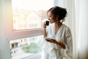Woman drinking coffee by window