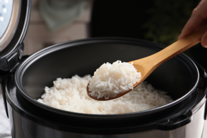 rice on wooden spoon over rice cooker