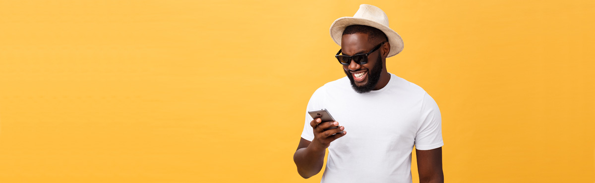 Young man wearing hat holding phone infront of a yellow background