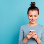 young woman holding phone with blue background