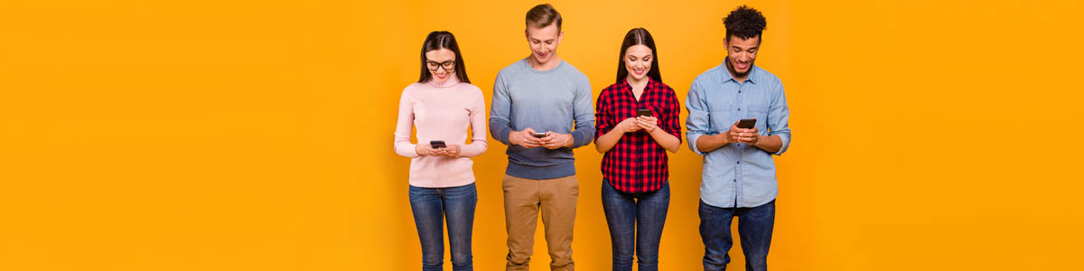 Four people holding and looking at mobile phones against yellow background