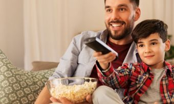 Young father and son watching TV together