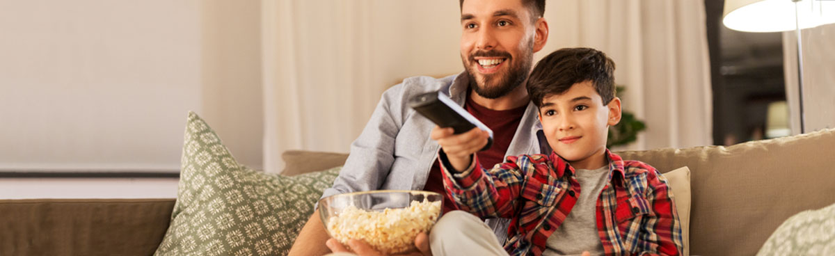 Young father and son watching TV together