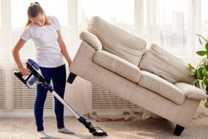 woman in white shirt and jeans cleaning carpet