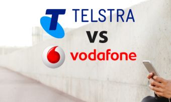 Woman holding phone with Telstra and Vodafone logos