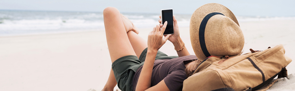 Young woman lying on beach sing mobile phone