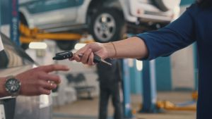 Car workshop - woman gives the keys of car for mechanic