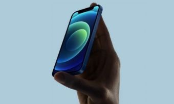 An iPhone 12 being held in front of a blue background