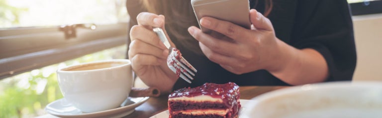 Woman eating food while on phone