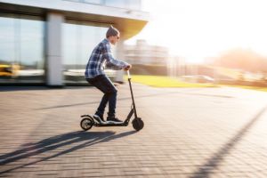 Young man in casual wear on electric kick scooter 