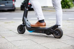 Low Section Of A Businessman Standing On Electric Scooter At Street