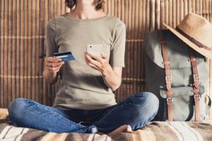 oung woman on vacations using smartphone and credit card