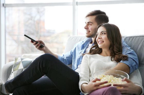 Young couple watching tv together with popcorn