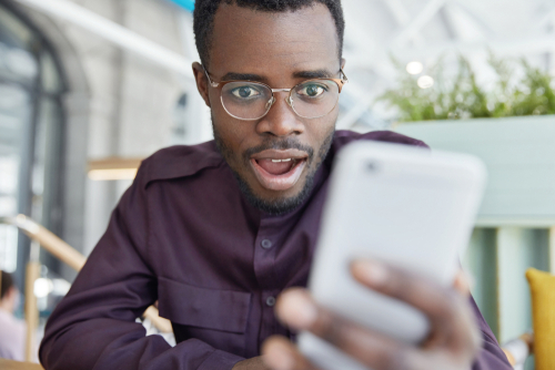 Young man looking surprised at smartphone