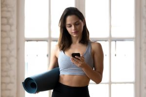 Woman with yoga mat on phone