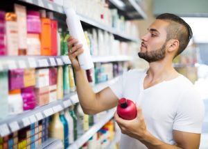 Attractive man buying shampoo in shopping mall