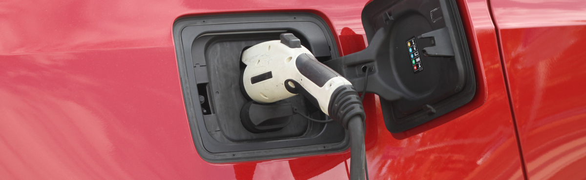 electric vehicle charging plugged into red car