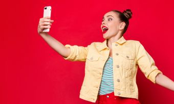 Young excited woman looking at phone against red background