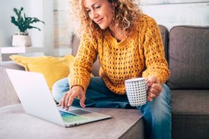 Lady sitting on couch with laptop and coffee