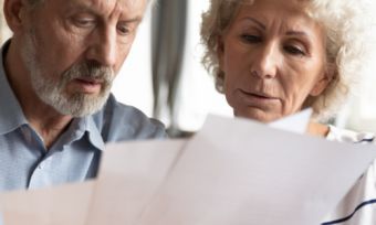 Mature age couple reading energy bills at table