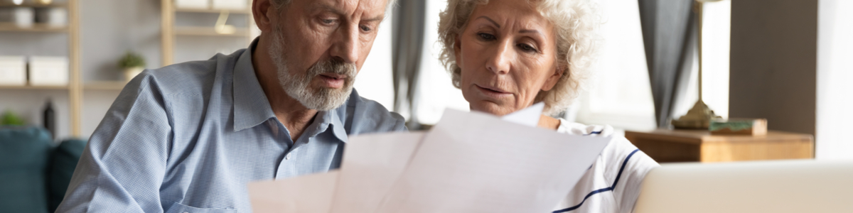 Mature age couple reading energy bills at table