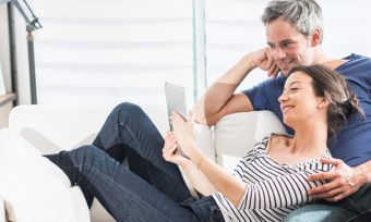 Couple sitting on sofa looking at tablet