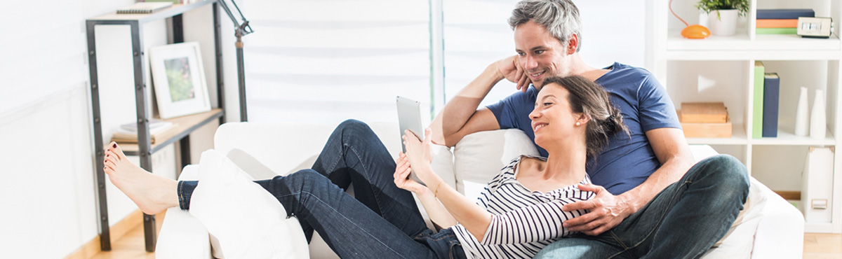 Couple sitting on sofa looking at tablet