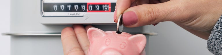 Hand putting coin in piggy bank with gas meter