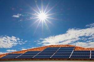 House with solar panels on roof with sun in background