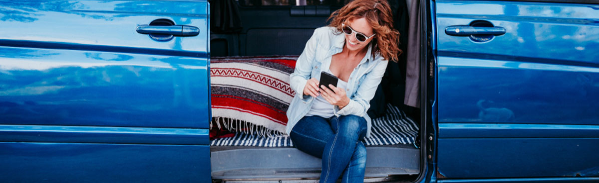 Travelling woman in van checking phone