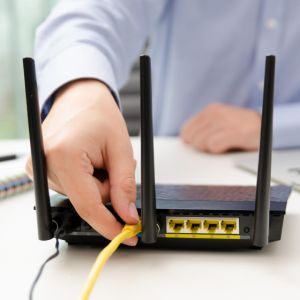 A person disconnecting an ethernet cable from a modem