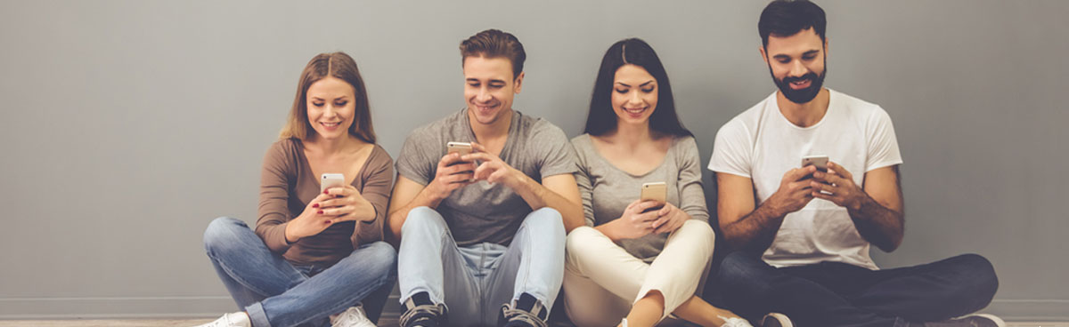 Four young people looking at their mobile phones