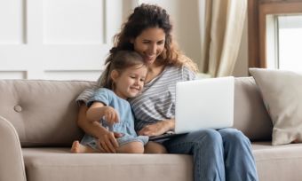 Woman and daughter on sofa looking at laptop computer in the home