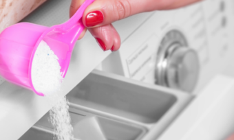 person pouring laundry powder into a front loader washing machine