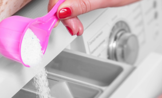 person pouring laundry powder into a front loader washing machine