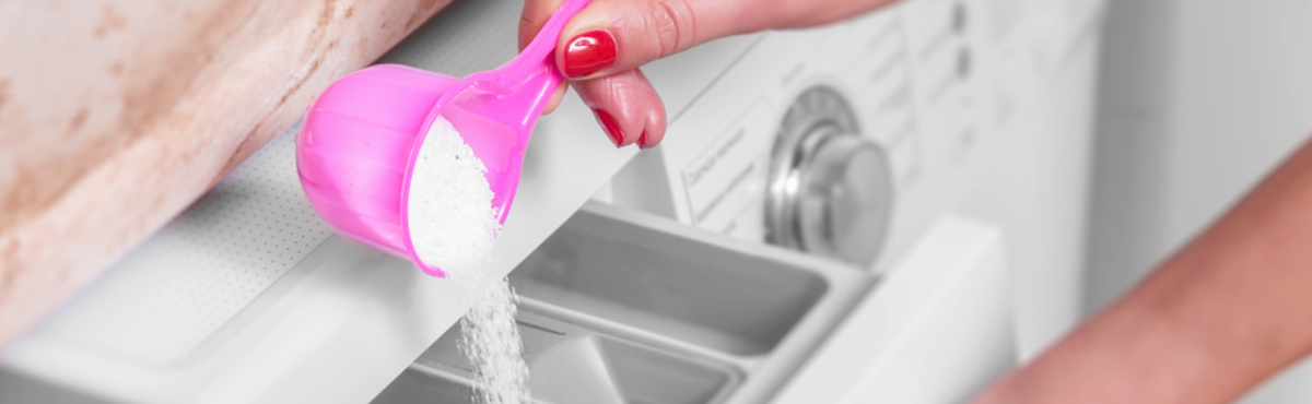 person pouring laundry powder into a front loader washing machine