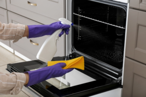 Person cleaning oven with oven cleaner spray