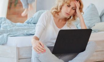 Frustrated woman using laptop in bedroom