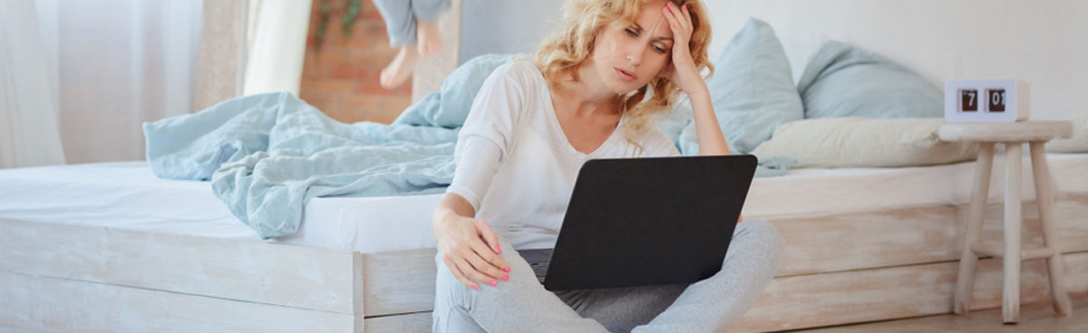 Frustrated woman using laptop in bedroom