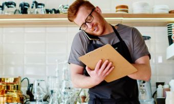 Young cafe owner taking business call