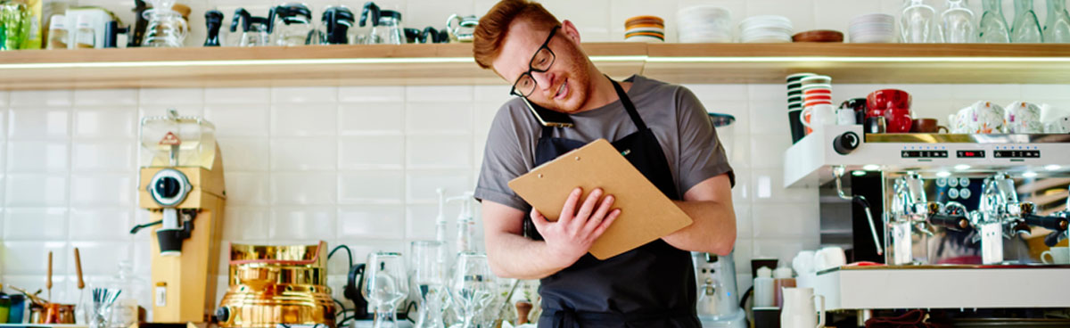 Young cafe owner taking business call