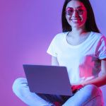 Woman using laptop against purple background